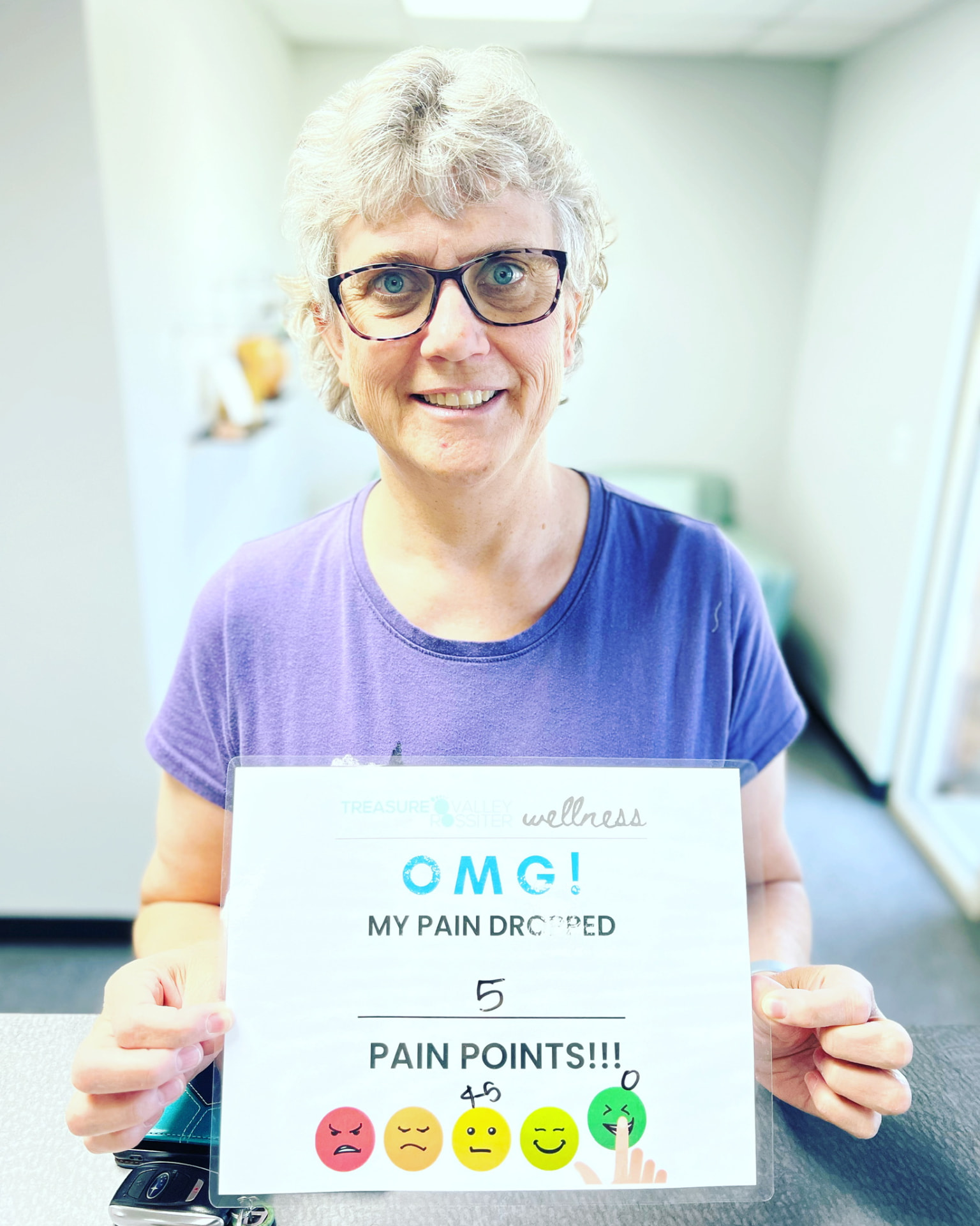 Real Treasure Valley Rossiter client holding a sign showing how much their discomfort dropped after a session (6 of 7)